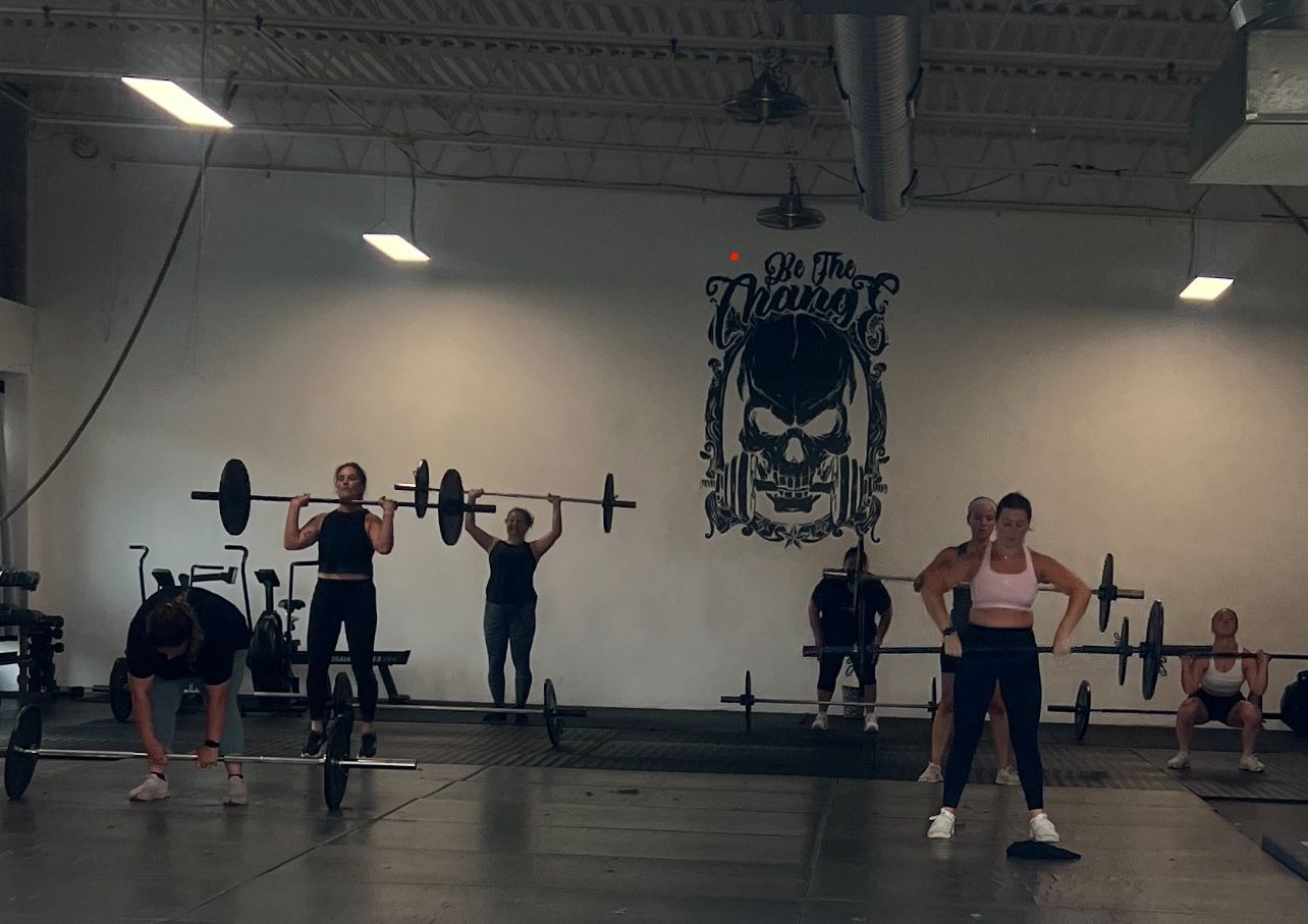 A group of people are doing exercises in a gym with a skull on the wall