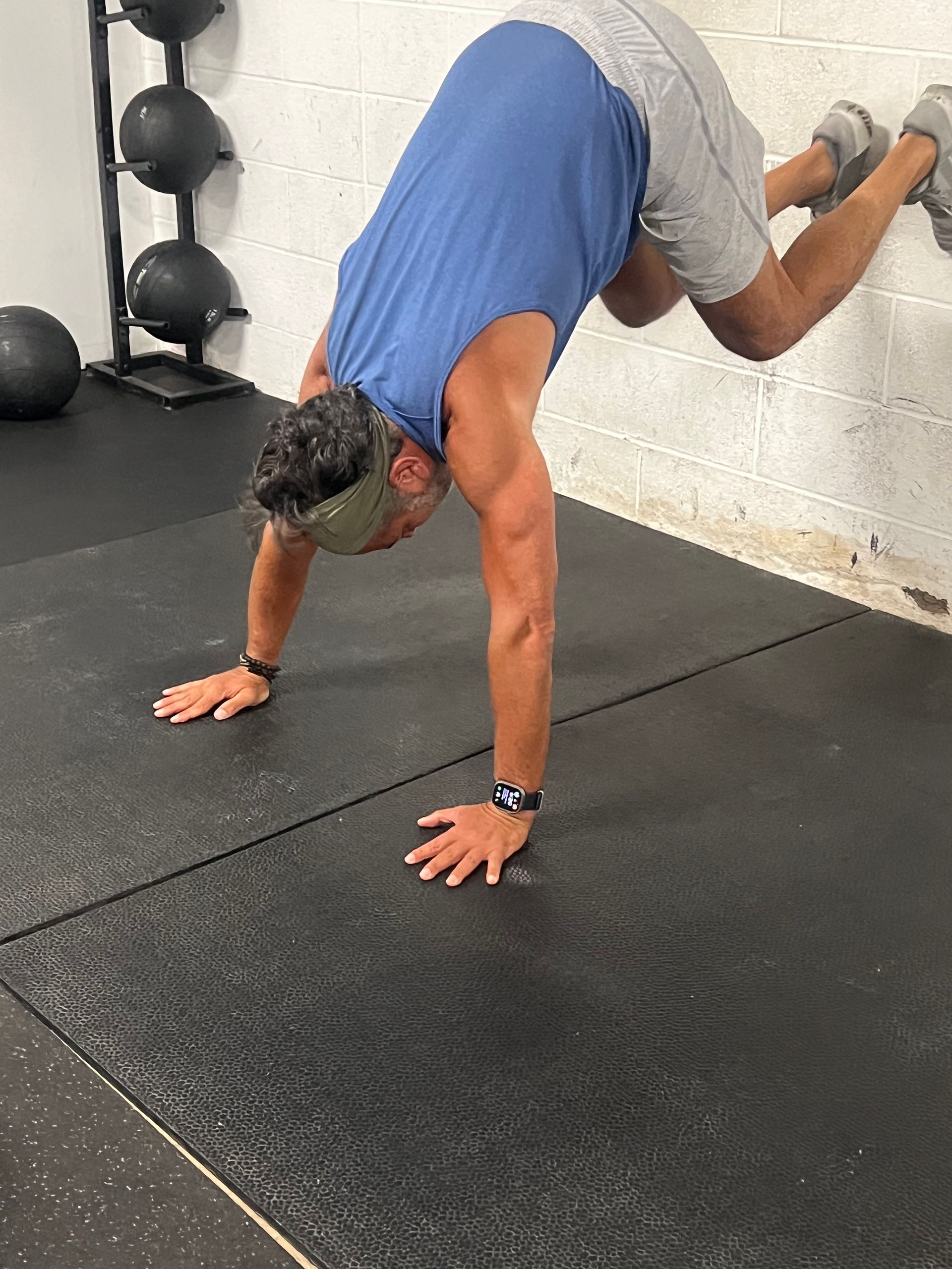 A man is doing a handstand on a mat in a gym.