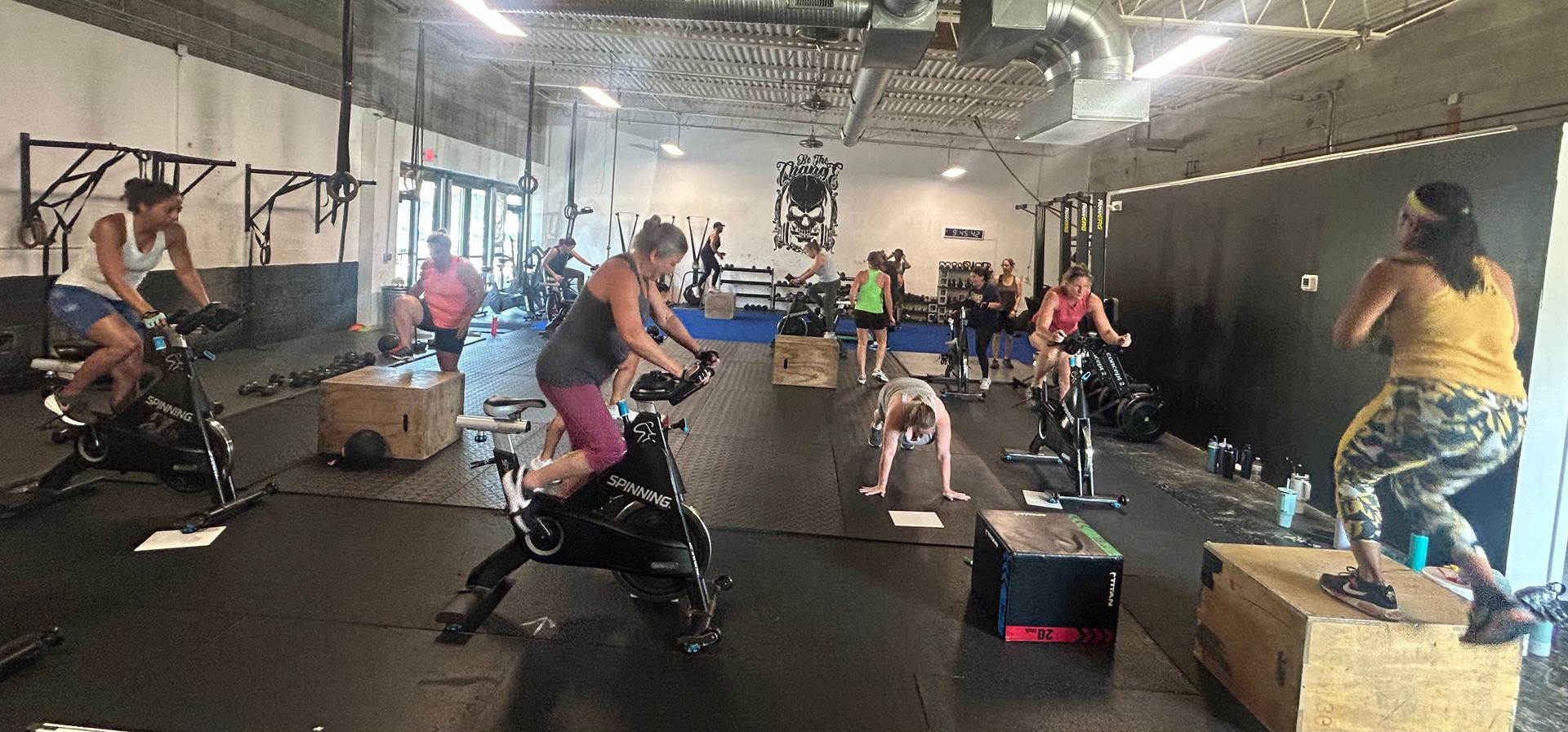 People exercising in a gym on stationary bikes and boxes during a group workout class