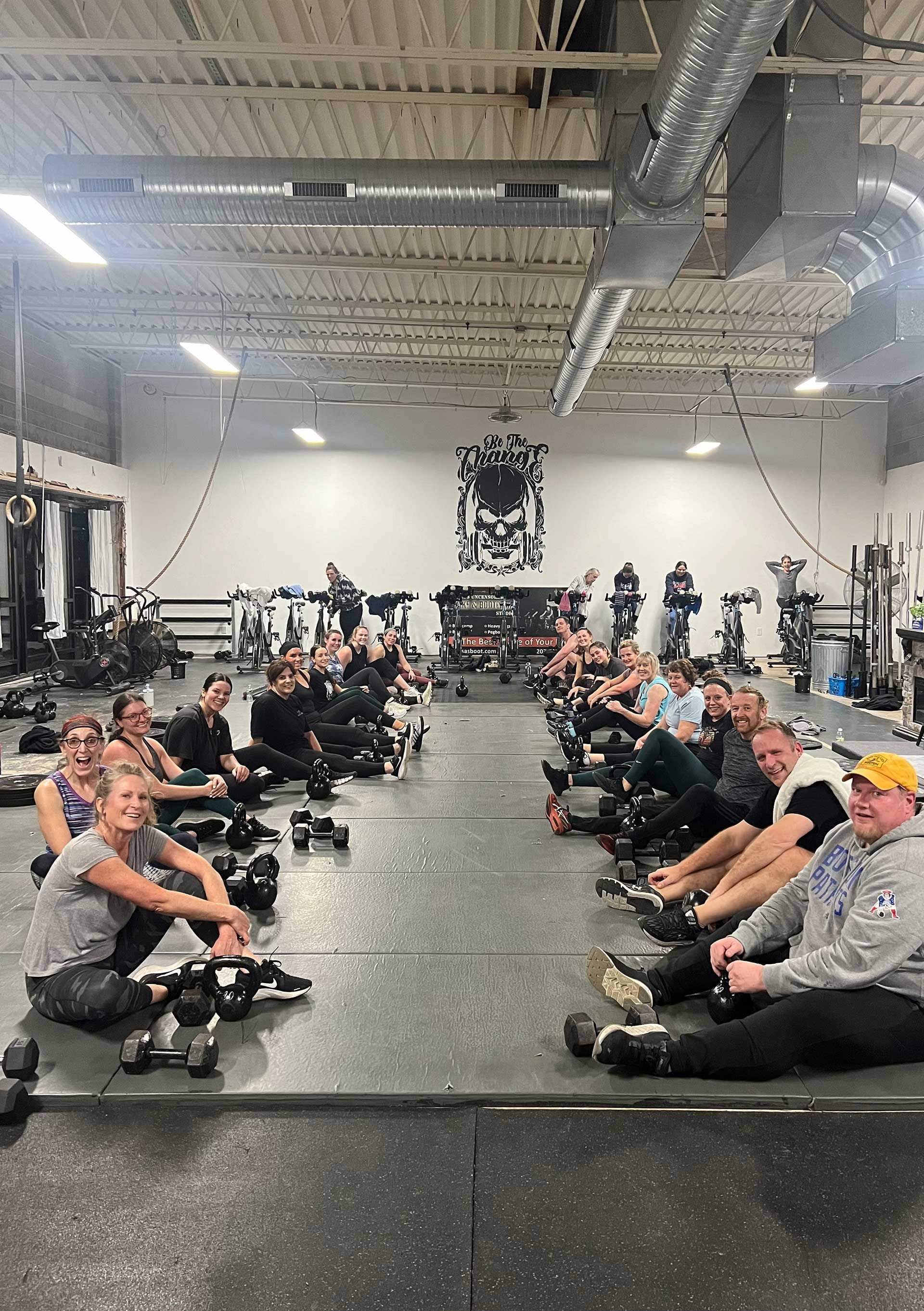 A group of people are sitting on the floor in a gym