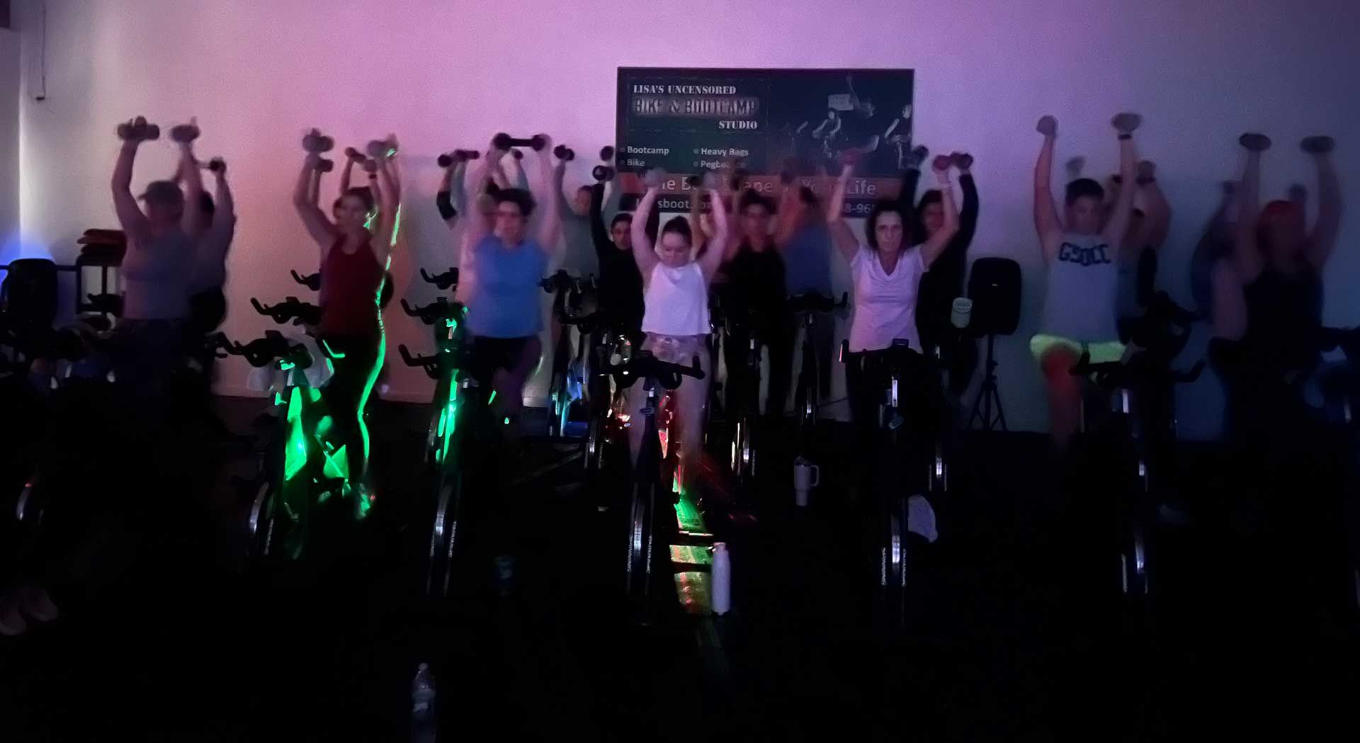 A group of people are riding exercise bikes in a dark room