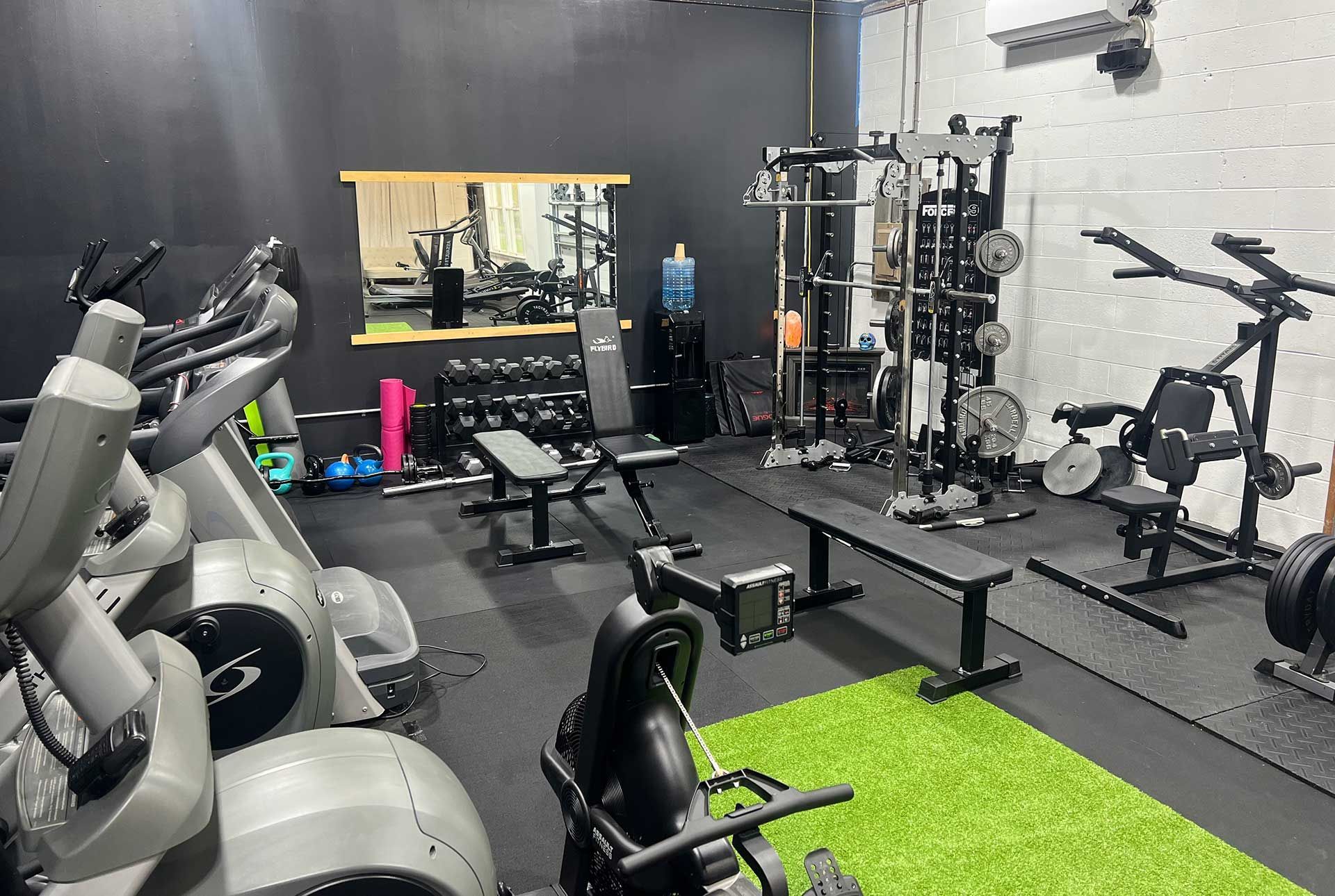 A gym filled with lots of exercise equipment and a green rug