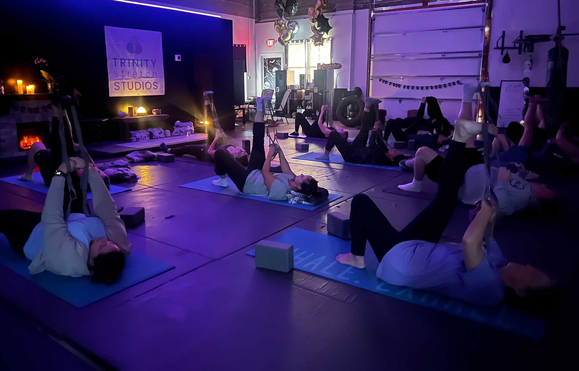 A group of people are doing stretches in a dark room