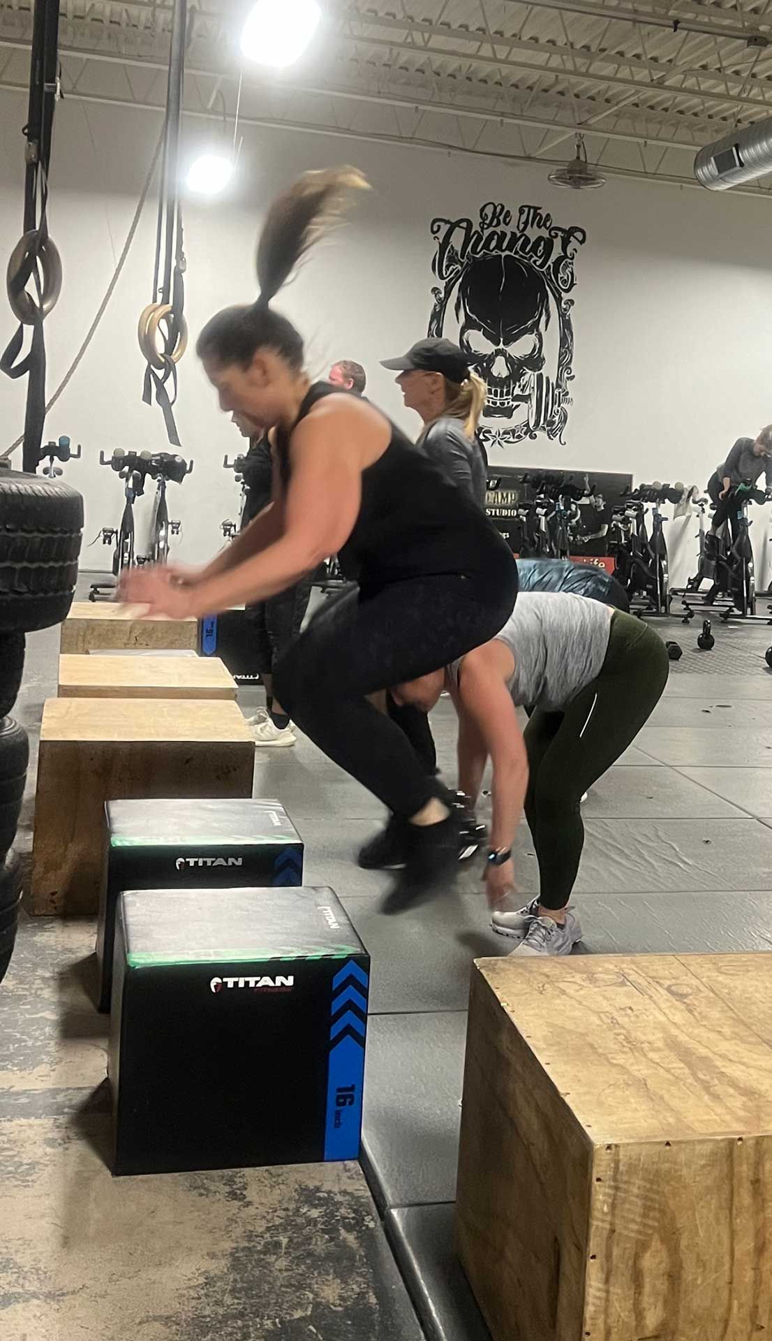 A group of people are jumping over wooden blocks in a gym