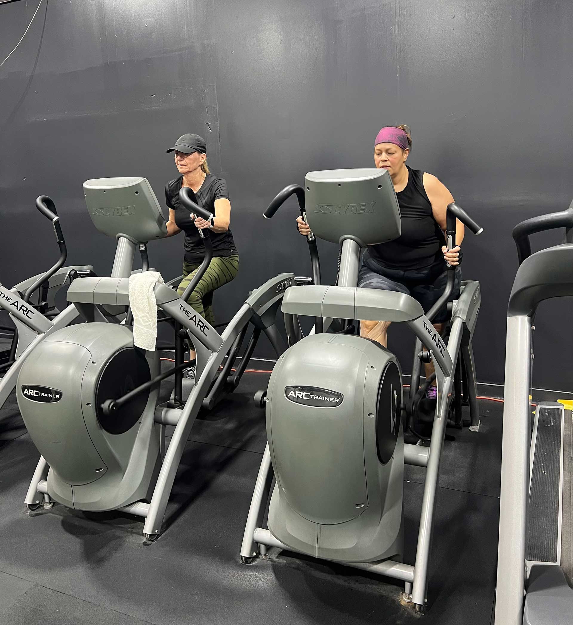 Two women are riding exercise bikes in a gym