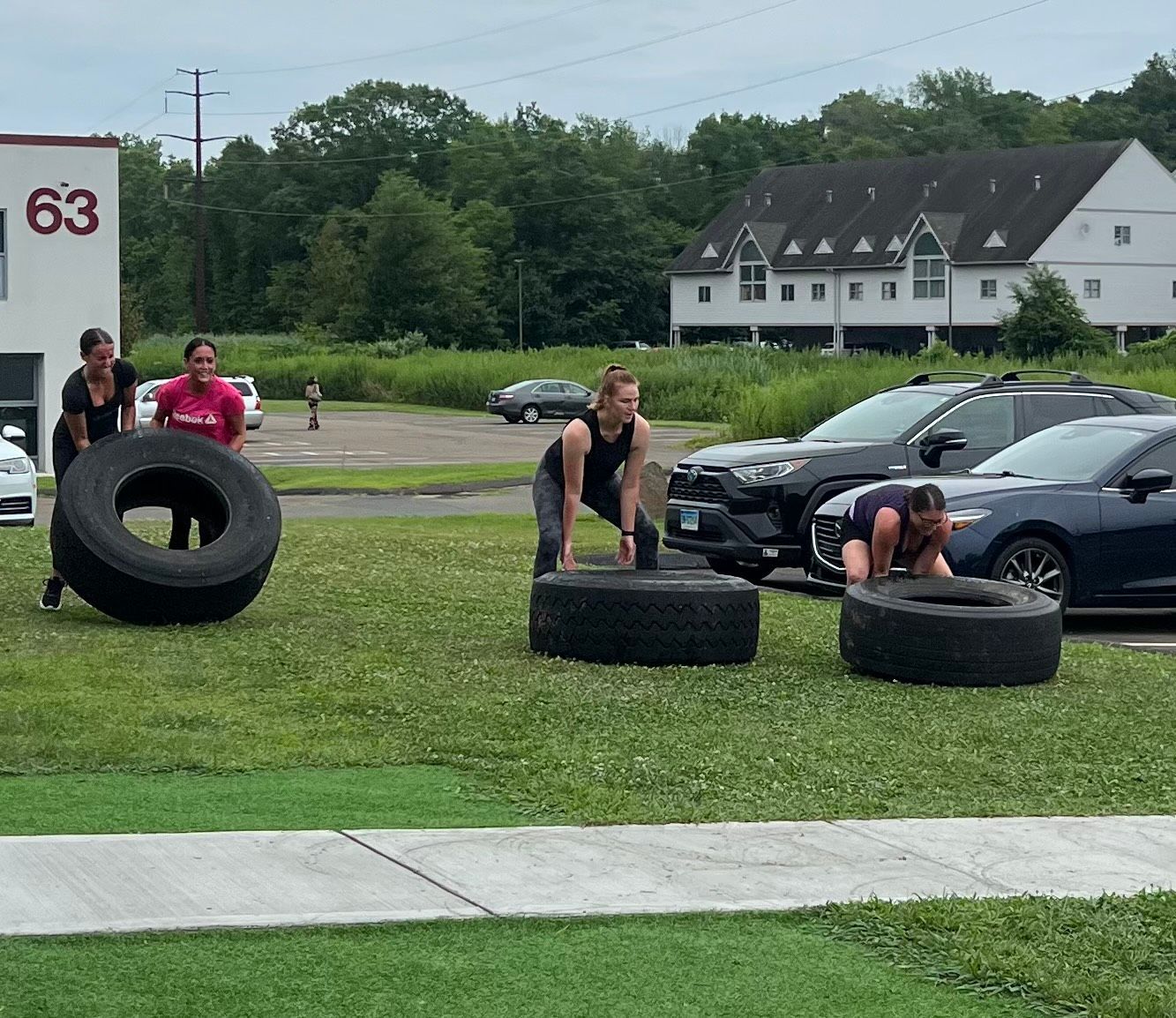 A group of people are pushing tires in a parking lot.