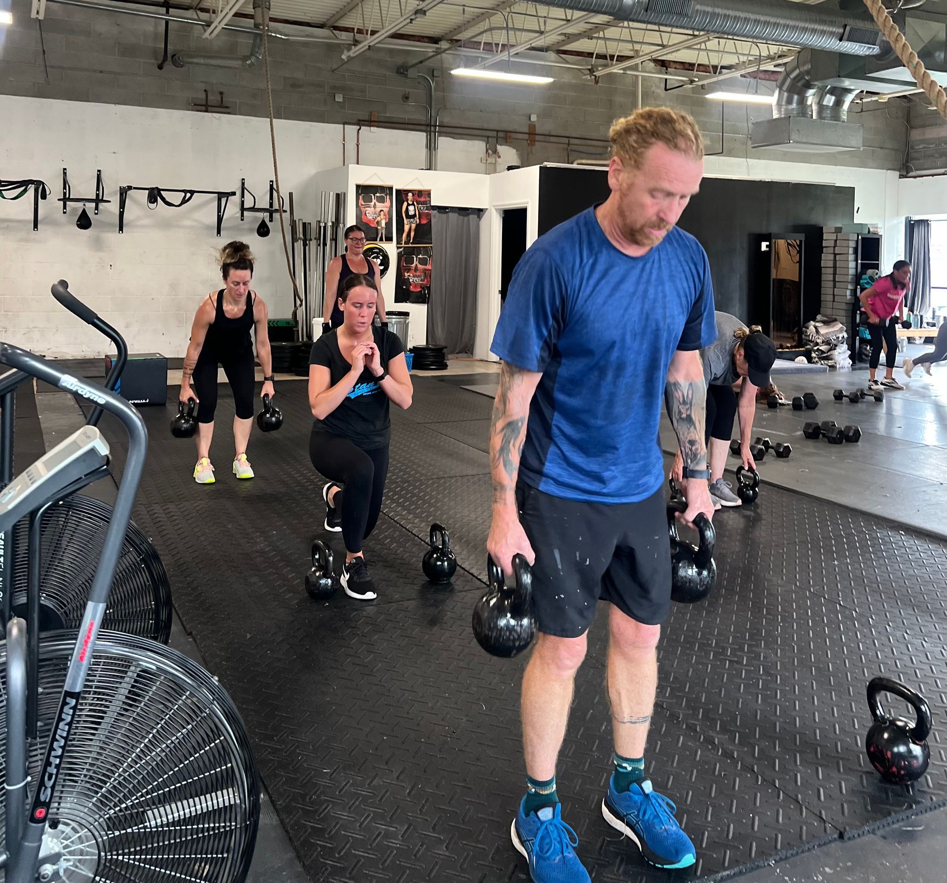 A group of people are lifting kettlebells in a gym