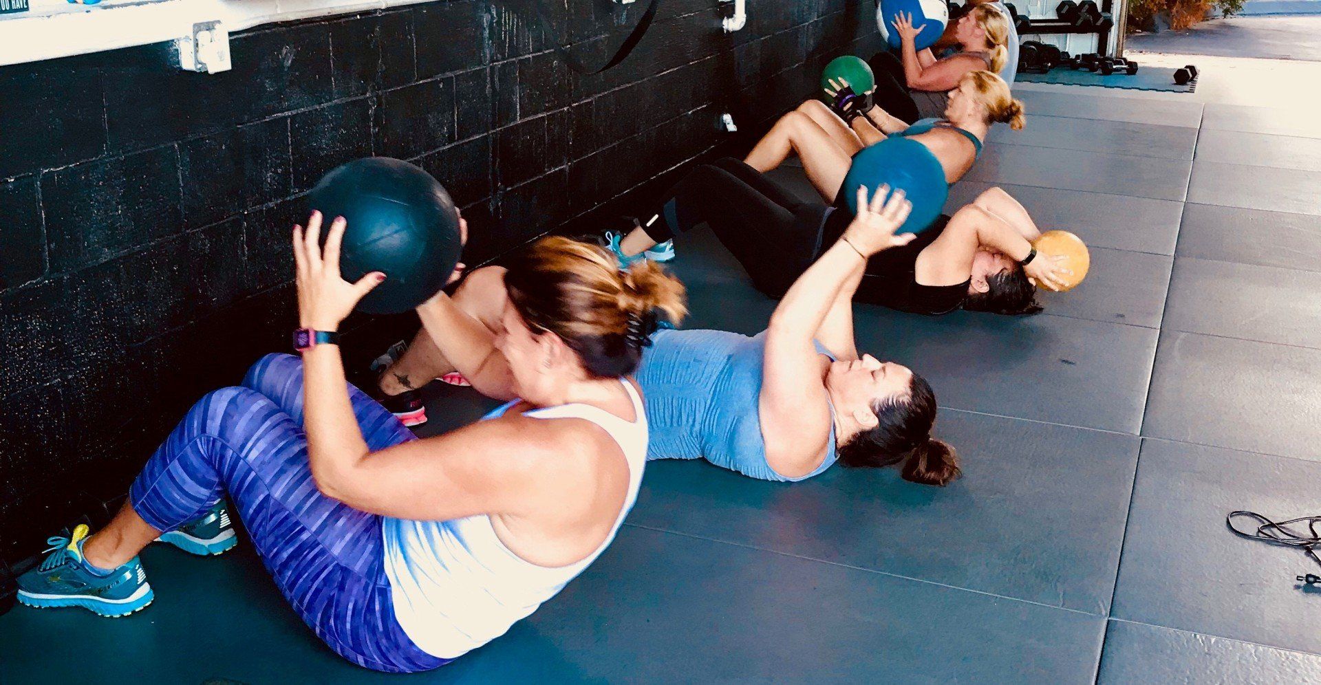 A group of women are doing exercises with medicine balls in a gym.