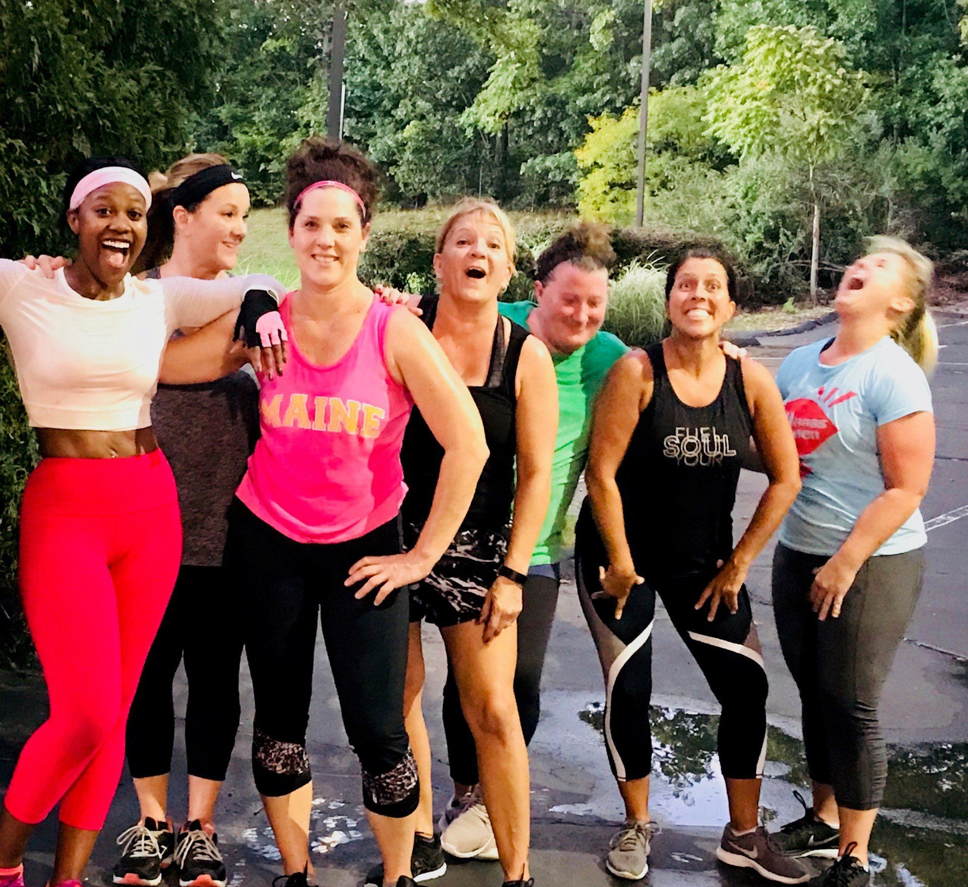 A group of women are posing for a picture and one of them is wearing a tank top that says iam
