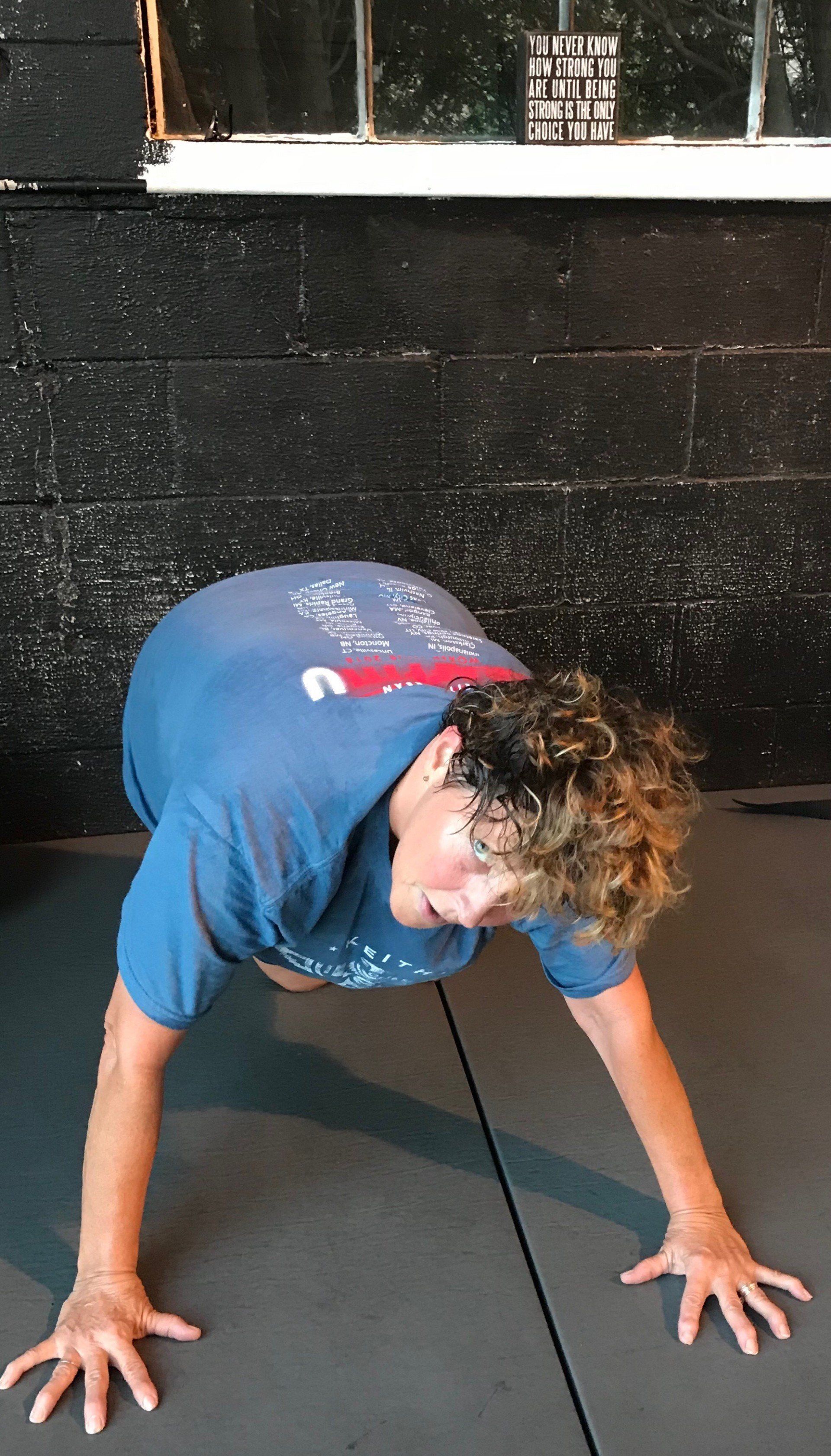 A man in a blue shirt is doing push ups on a mat.