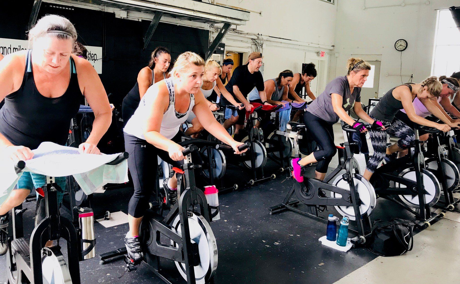 A group of women are riding exercise bikes in a gym.