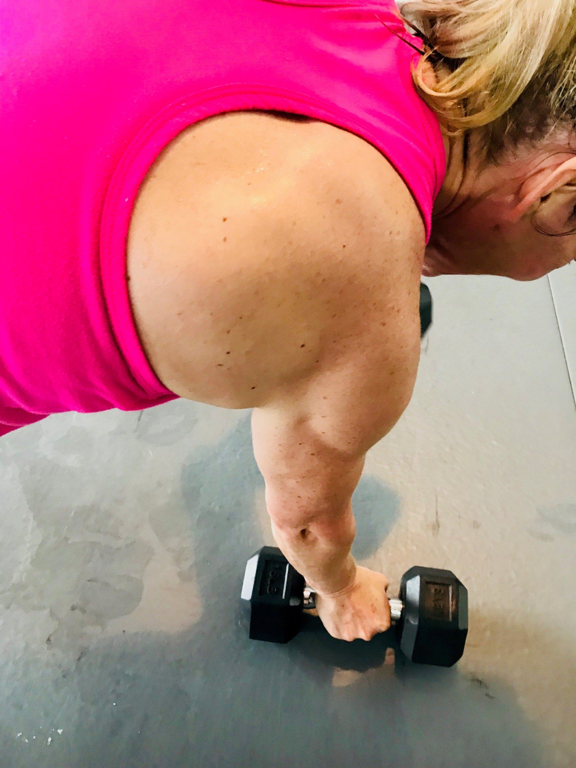 A woman is doing push ups with a dumbbell