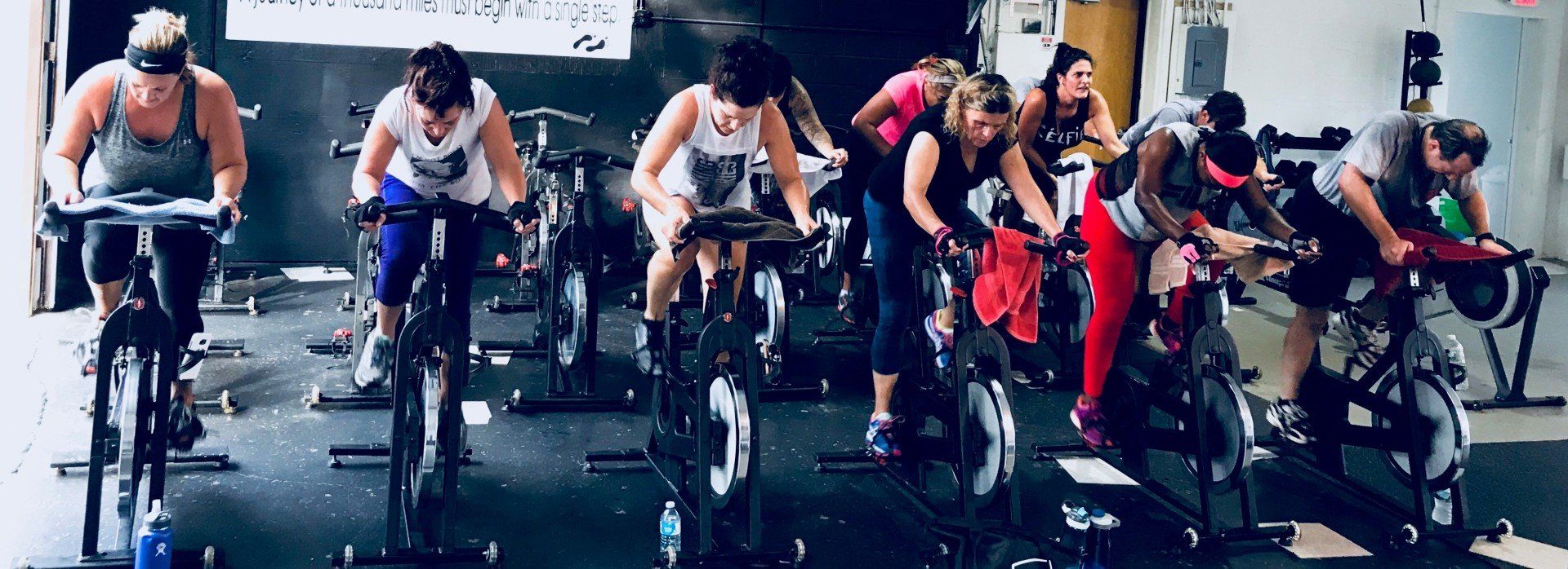 A group of people are riding exercise bikes in a gym.