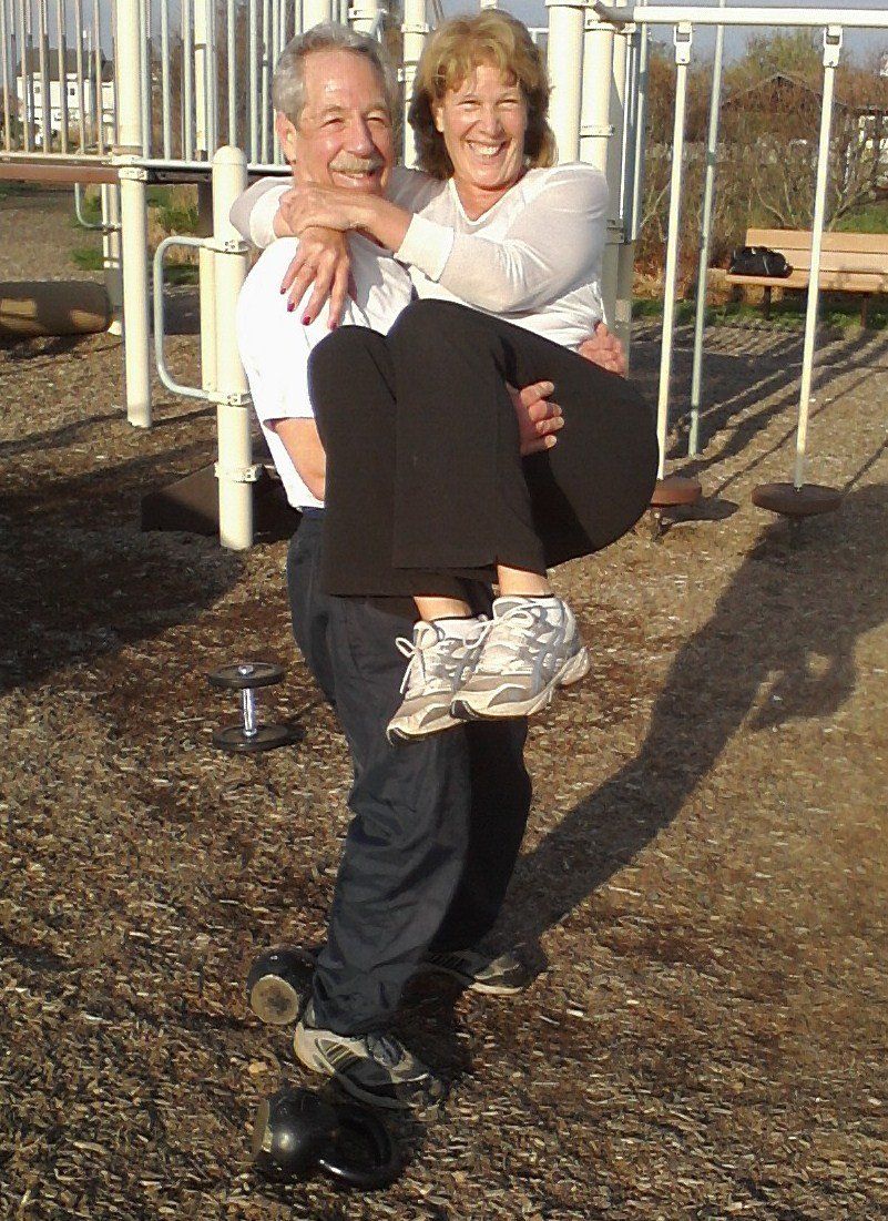 A man is carrying a woman on his back in a park