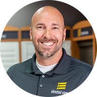 Man with a beard smiling, wearing a gray polo shirt with 