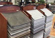 Carpet samples on display in a showroom. Various colors and patterns stacked in wooden racks.