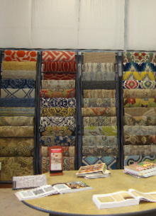 Carpet samples in various patterns and colors displayed on racks, with design magazines on a table.
