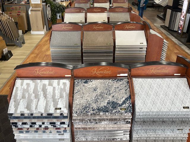 Displays of Karastan brand flooring samples in a showroom, showcasing various colors and patterns.