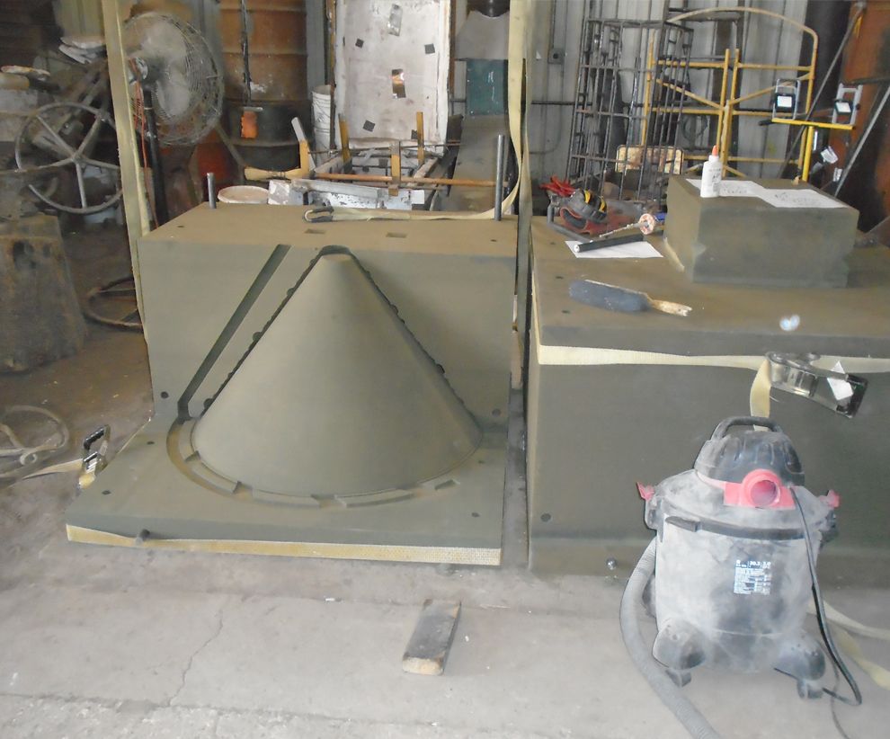 Industrial workshop with large concrete molds, metal supports, and a shop vacuum on the floor