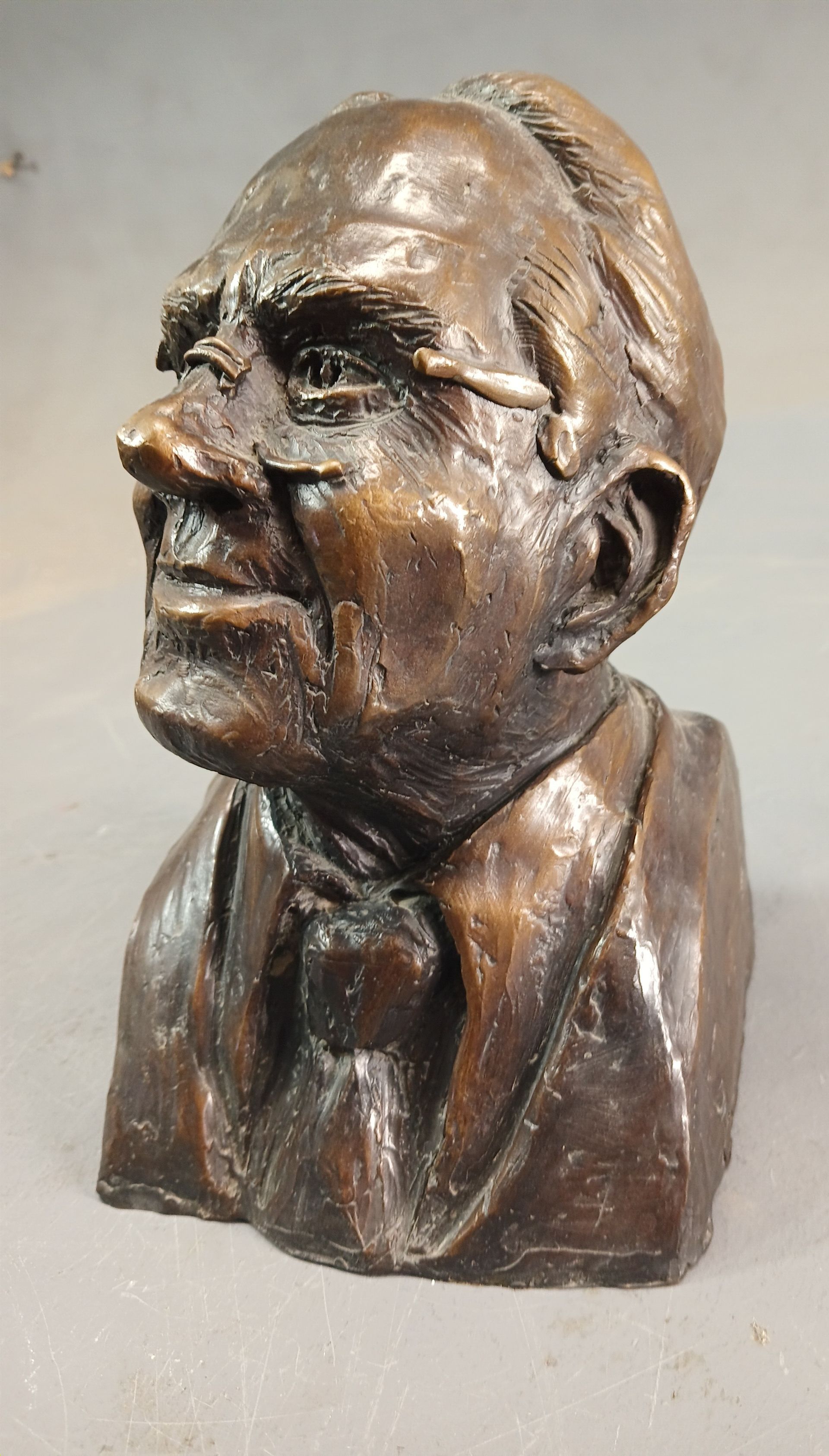 Bronze bust of a man in a suit, shown in profile with a thoughtful expression.