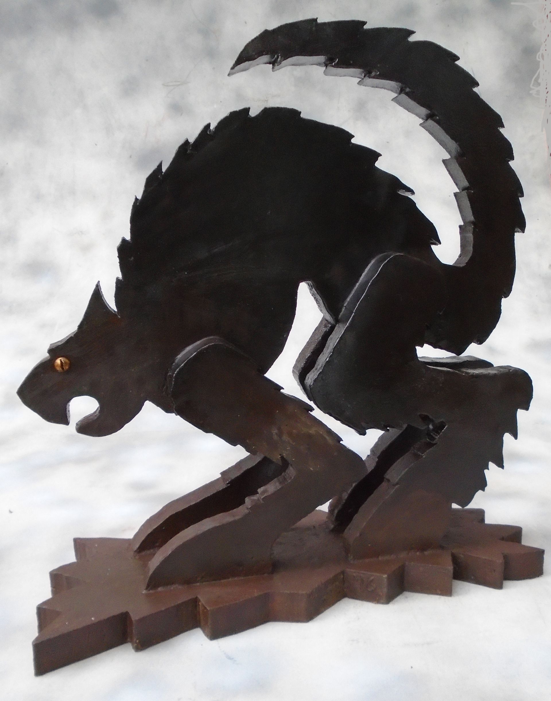 Dark brown wooden squirrel sculpture crouching on a branch, with an arched tail and bright eyes.