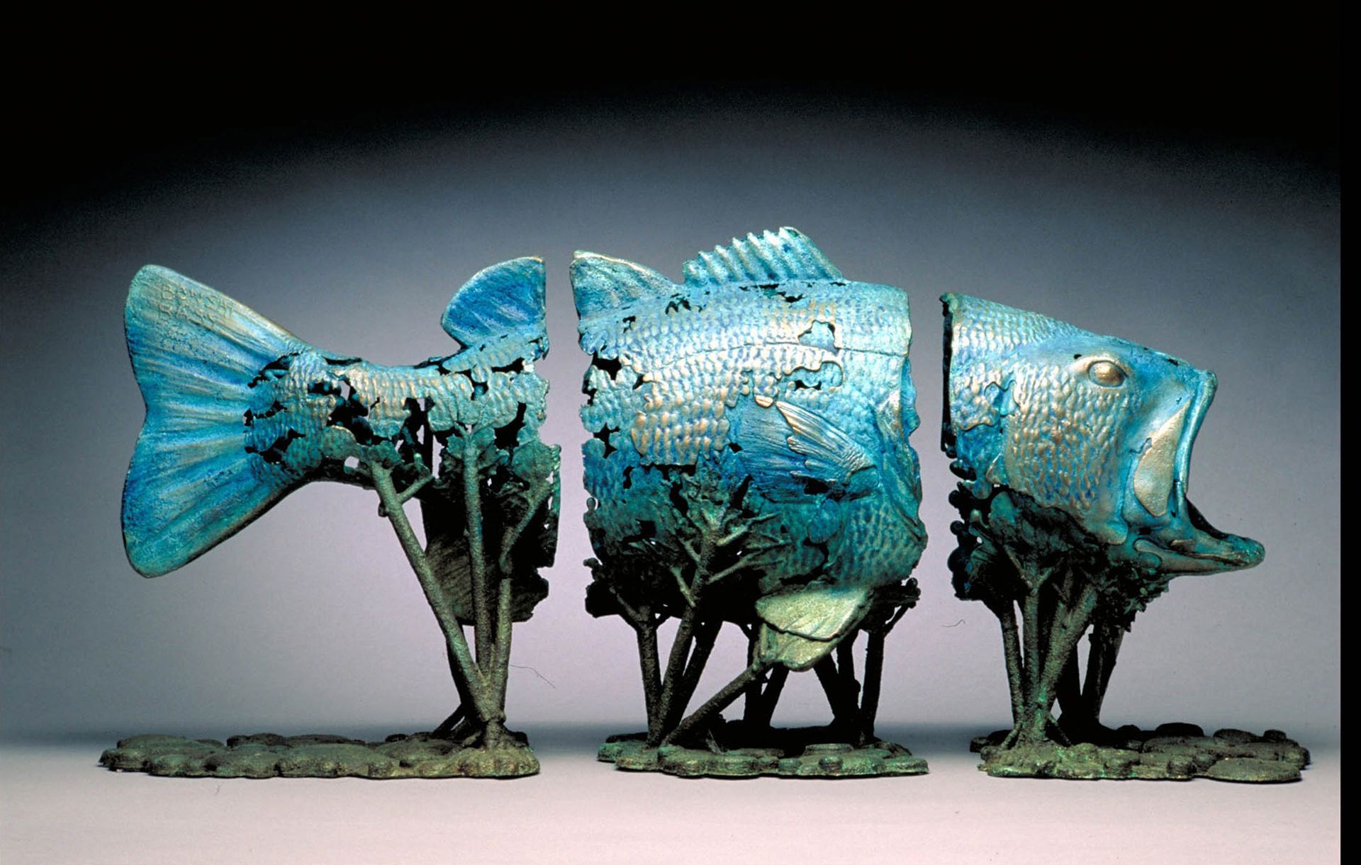 Blue fish sculpture made from metal scraps, mounted on a plain background