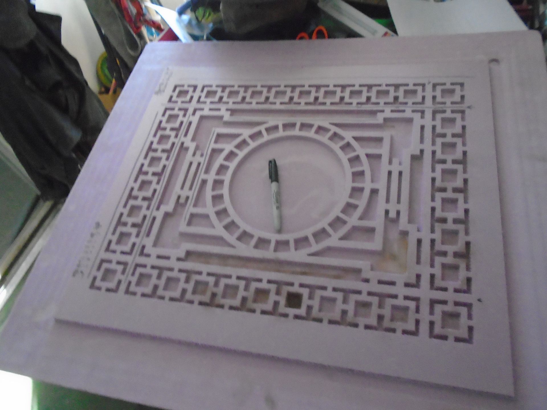 Decorative square wall clock with a geometric maze-like pattern and a central white clock face