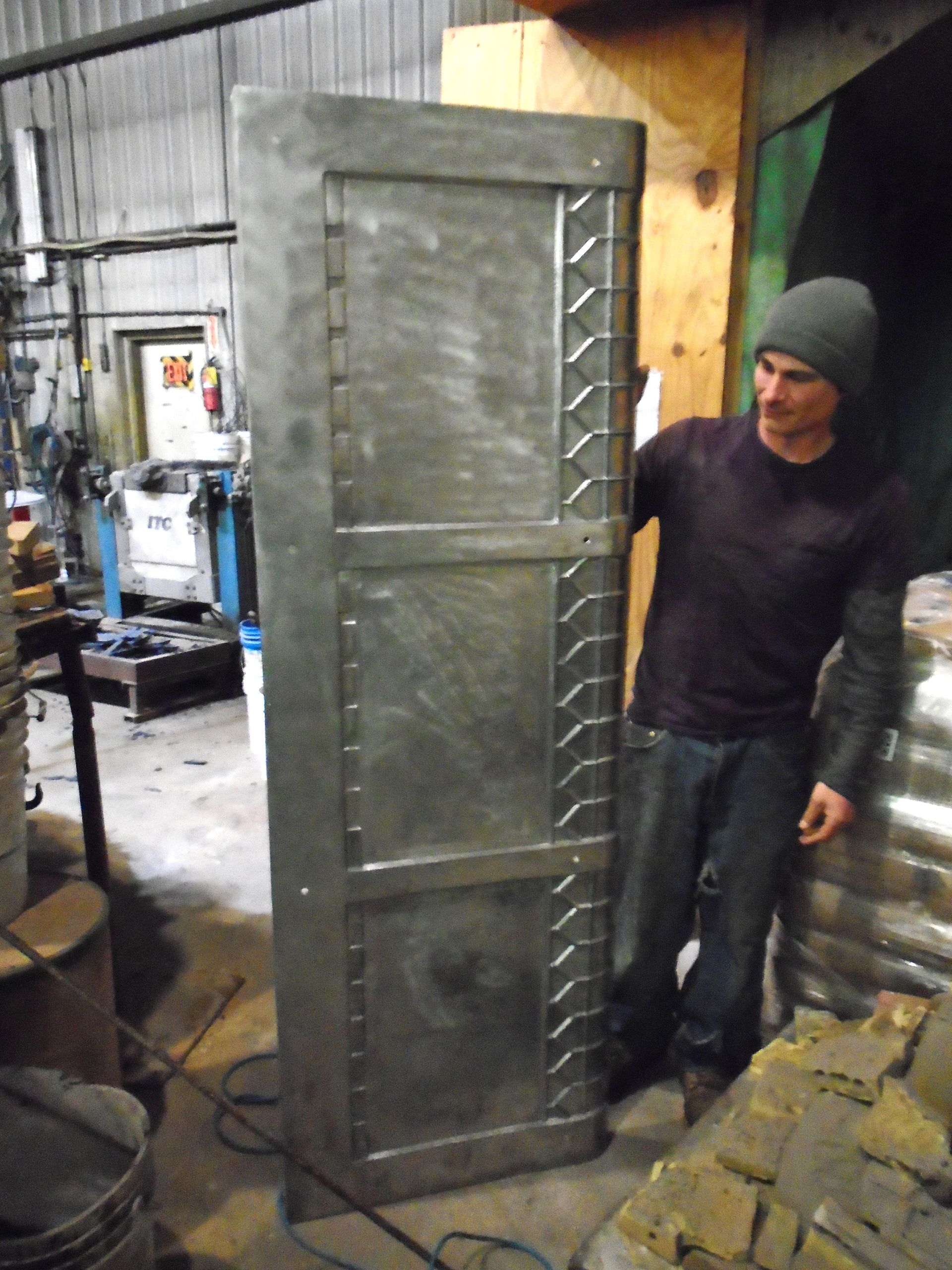 Man standing beside a large gray metal cabinet in an industrial workshop