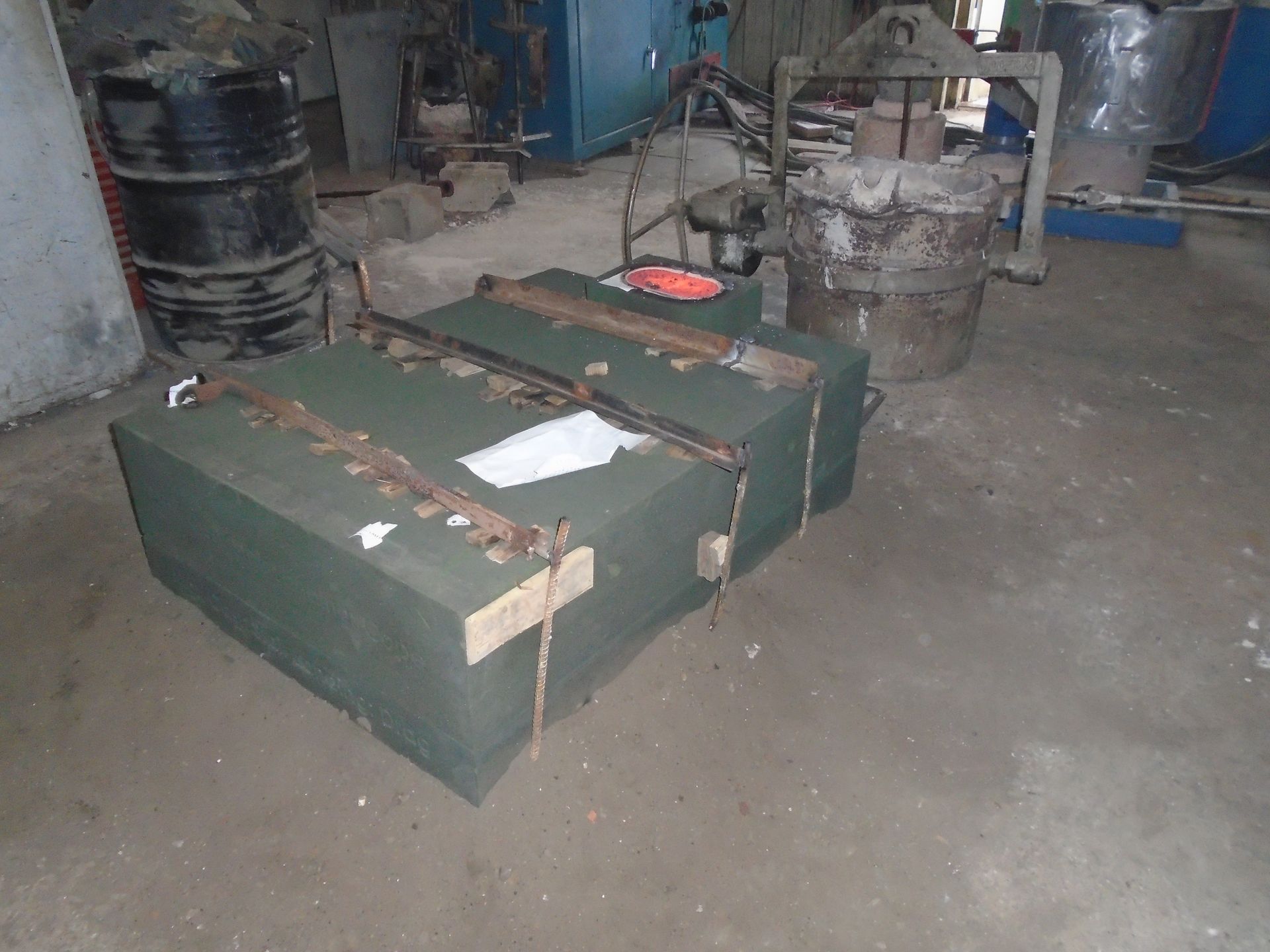 Green strapped shipping crates in a workshop beside industrial equipment.
