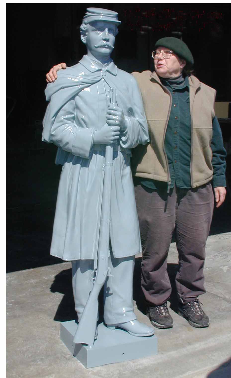 Person standing beside a blue-gray statue outdoors, arm around the statue's shoulder