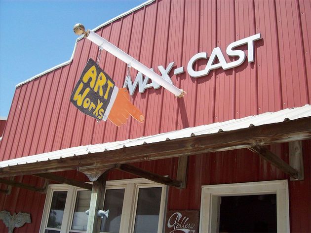 Exterior of a red building with a sign that reads "WAX-CAST" and an "ART WORKS" logo shaped like a paintbrush.