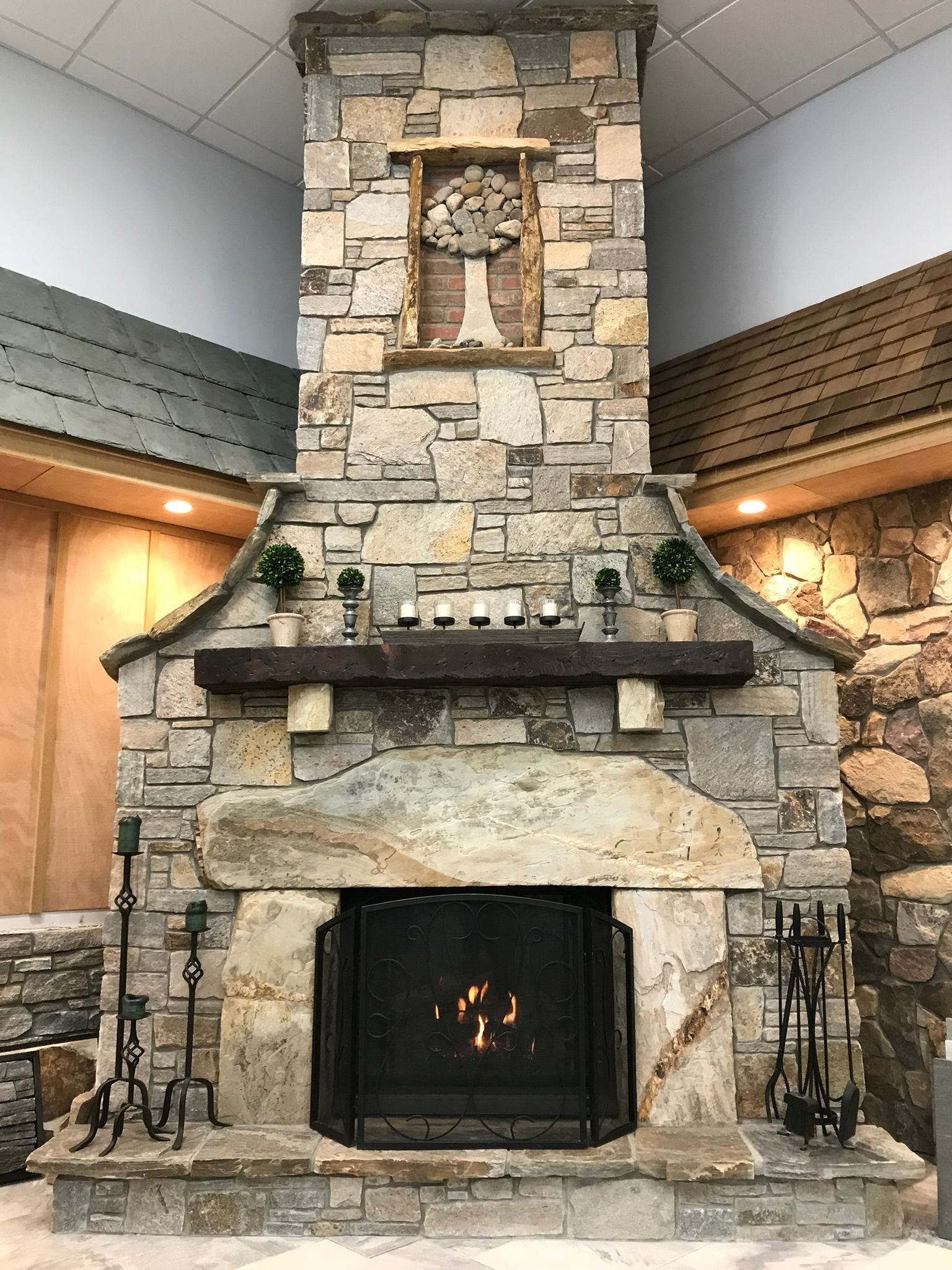 Stone fireplace with burning fire, wooden mantel, and decorative accents.