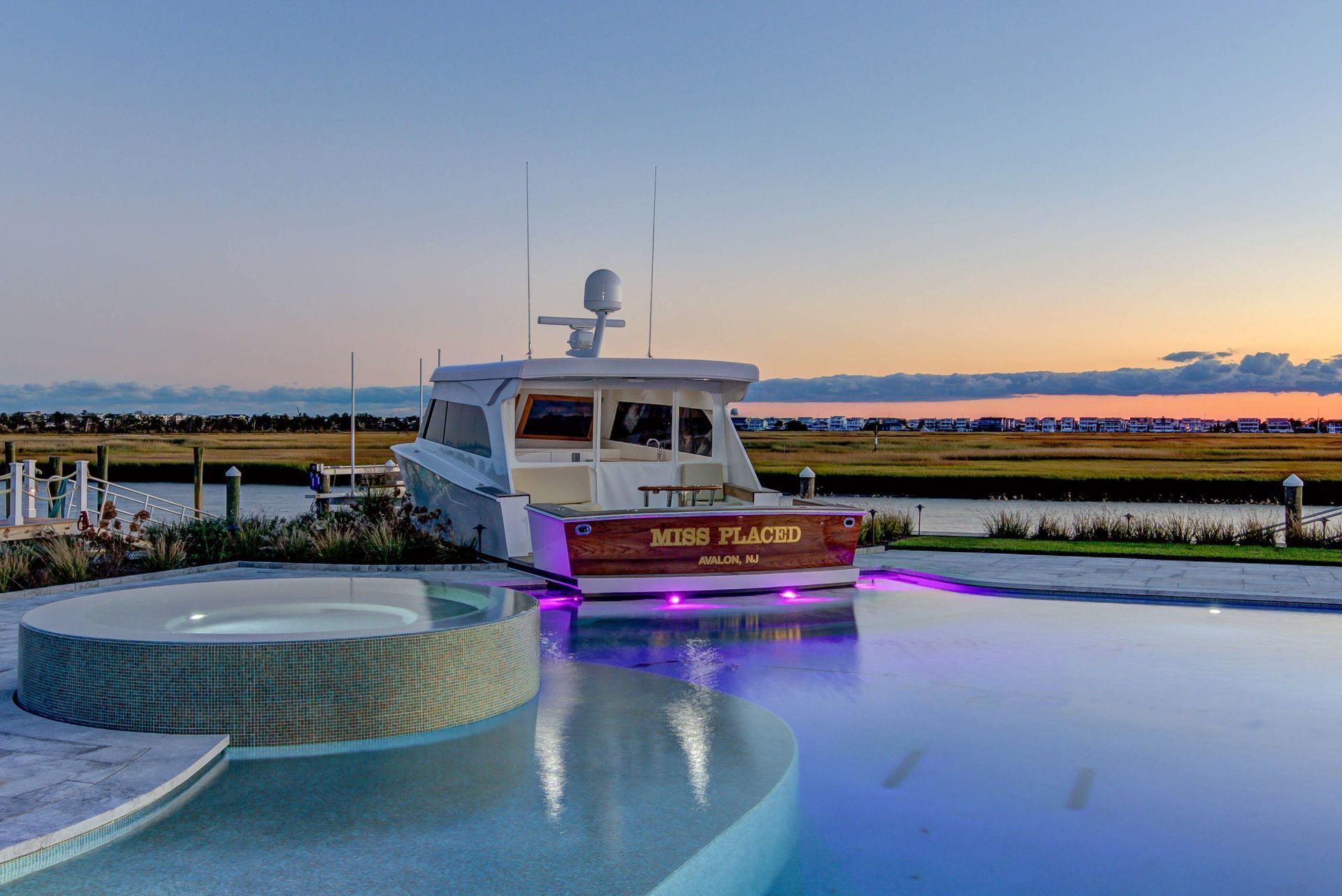 A luxury boat docked near a pool with a hot tub at sunset.