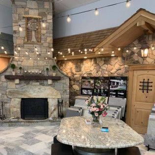 Stone fireplace and countertop display in a showroom, with string lights and wooden accents.