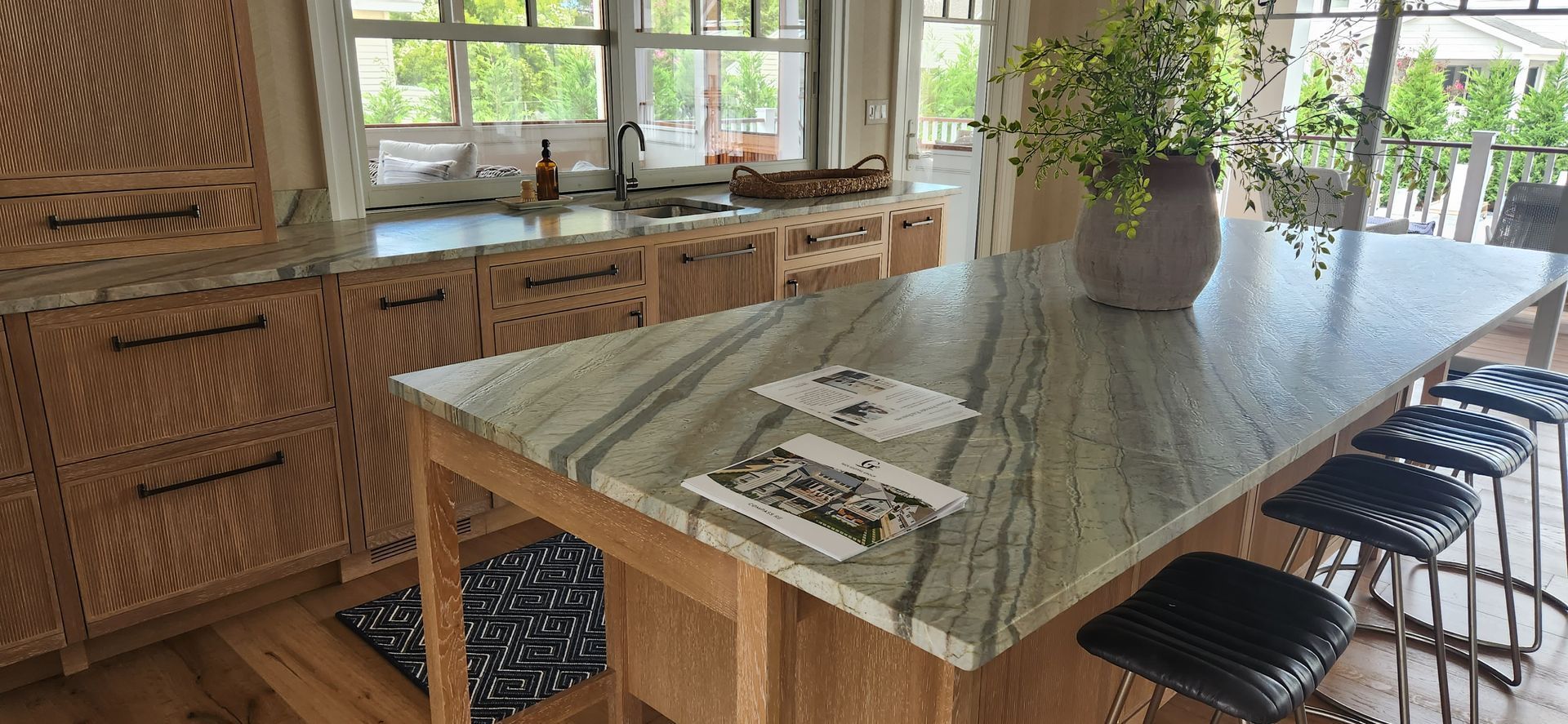 A kitchen with a granite countertop island and decorative wooden cabinetry.