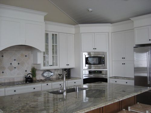 White kitchen with granite countertops, stainless steel appliances, and cabinets.
