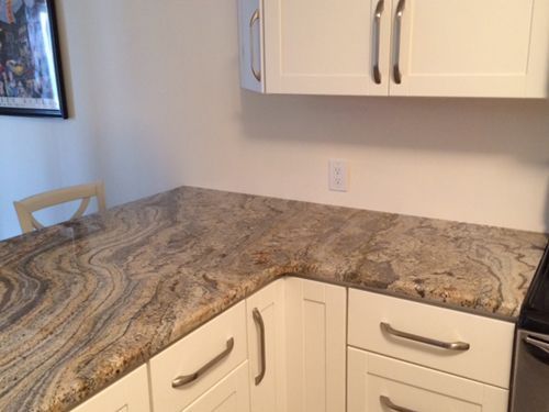 L-shaped kitchen counter with white cabinets and a swirling granite countertop.