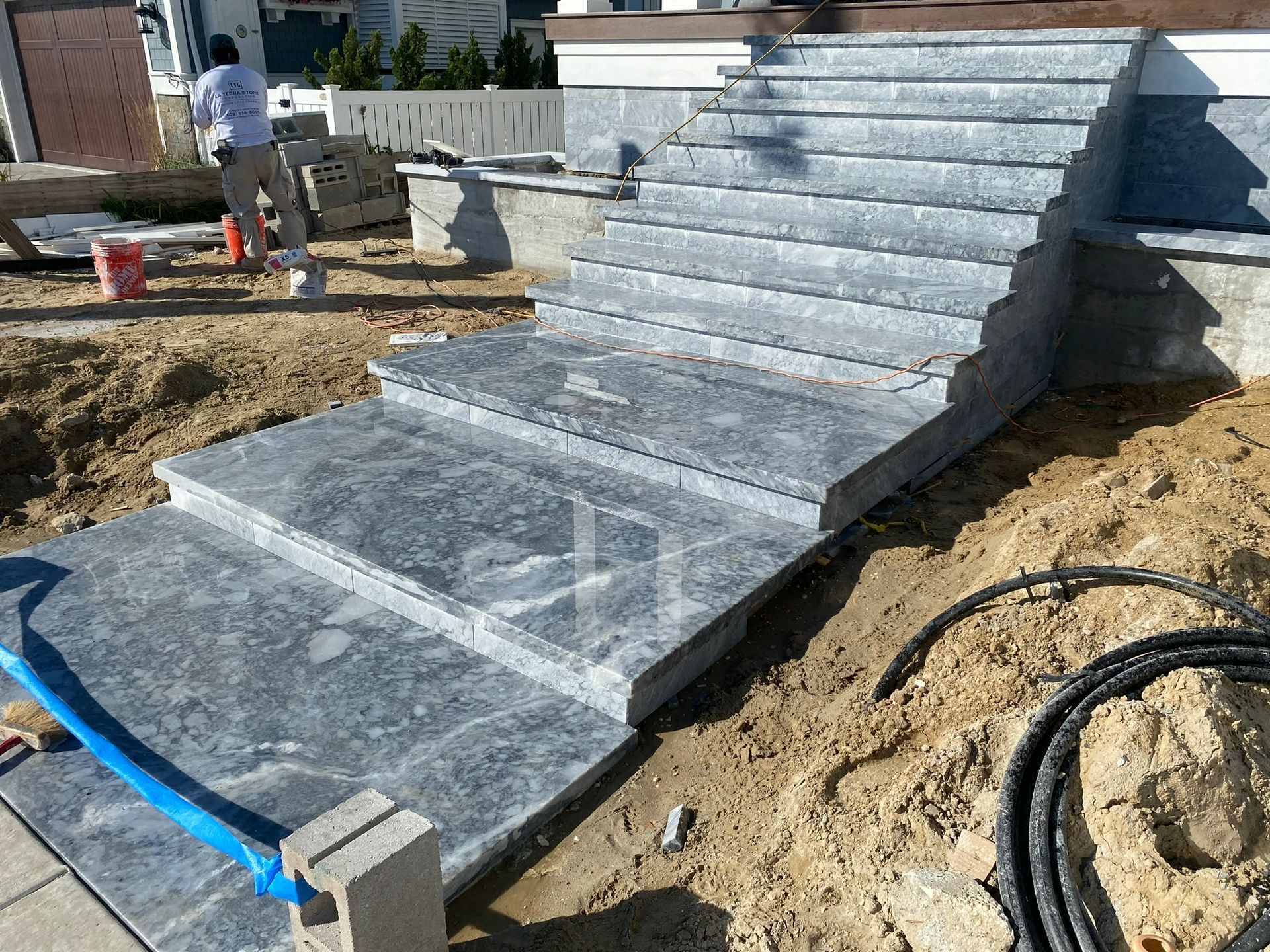 Granite steps under construction with a person working nearby. Earth and materials surround the stairs.