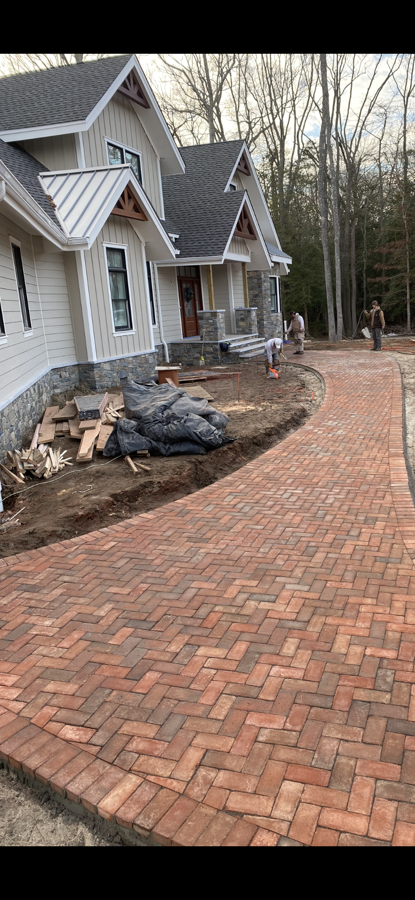 Red brick walkway leading to a house under construction.
