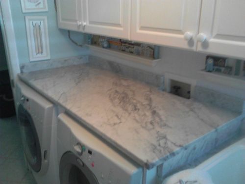 Laundry room with white cabinets, marble countertop, and washer/dryer.