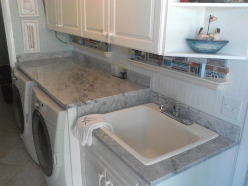 Laundry room with white cabinets, gray countertop, sink, and washer/dryer; a seashell nautical theme.