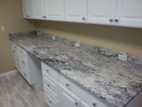 White cabinets and granite countertop in a room, with electrical outlets.