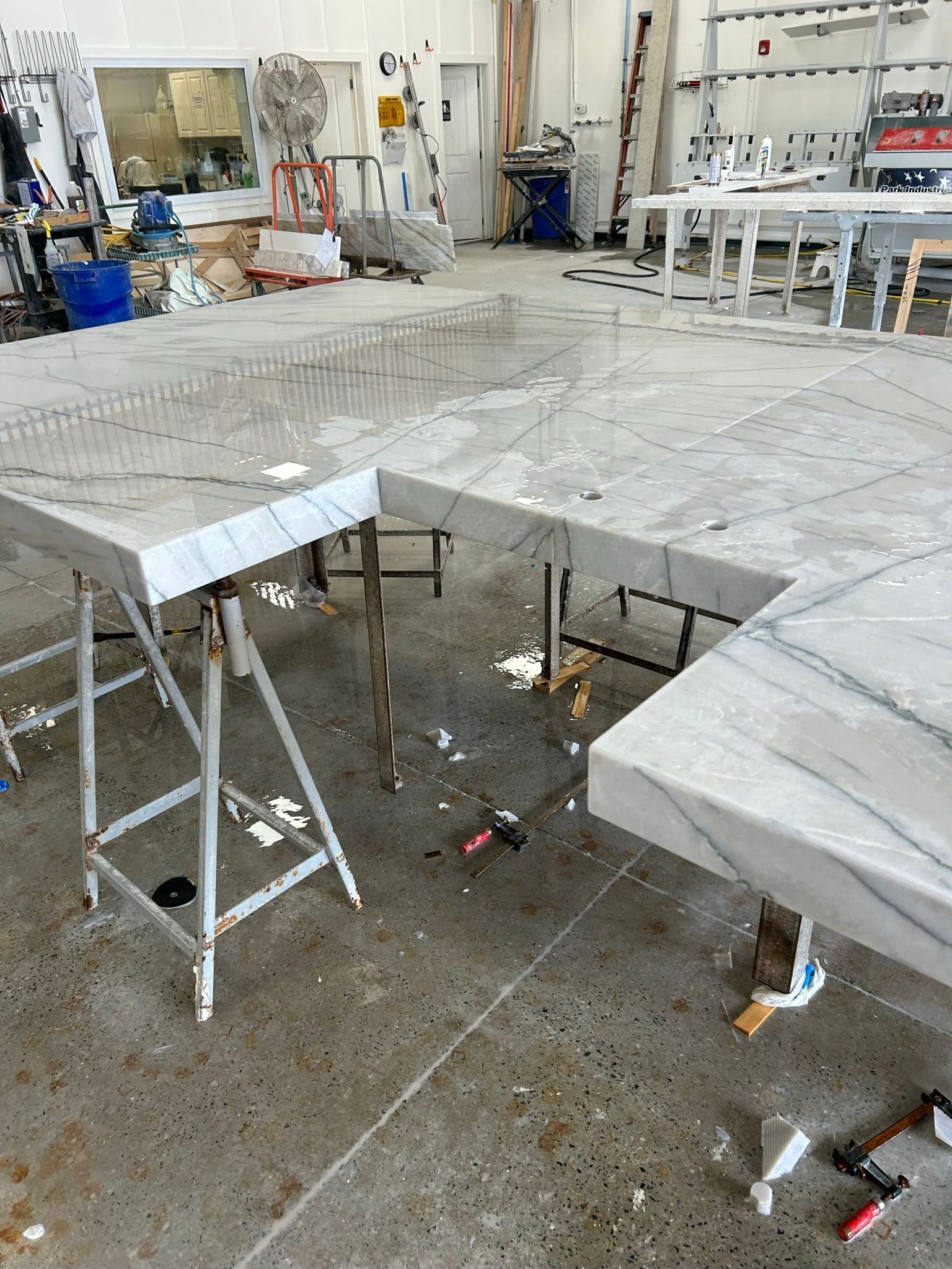 Three gray marble countertops on metal sawhorses in a workshop.