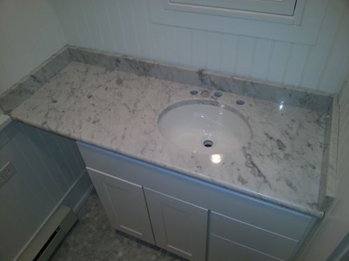 Bathroom vanity with white cabinet, granite countertop, and oval sink.