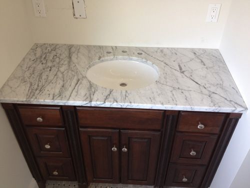 Dark wood bathroom vanity with marble countertop and oval sink.
