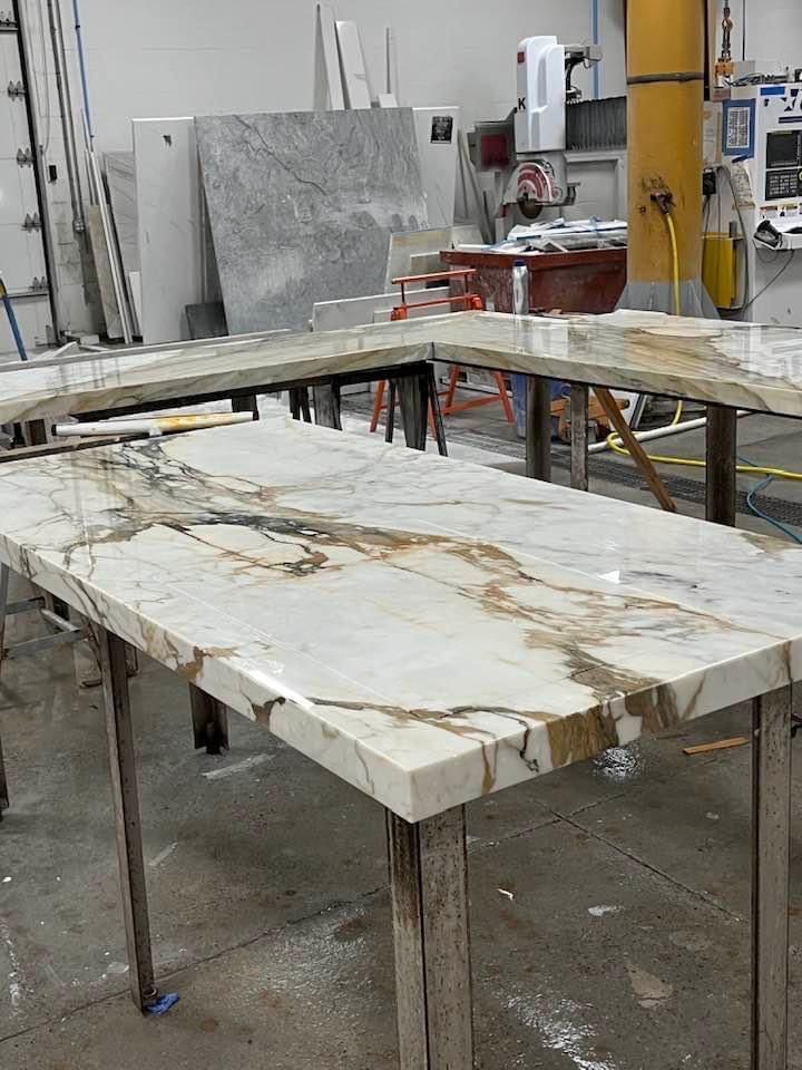 Marble countertops on wooden sawhorses in a workshop, showcasing the veining.