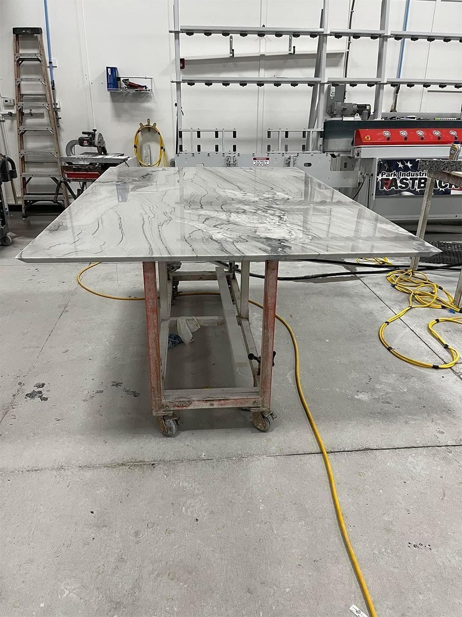 Large granite countertop on a red wheeled cart in a workshop setting.