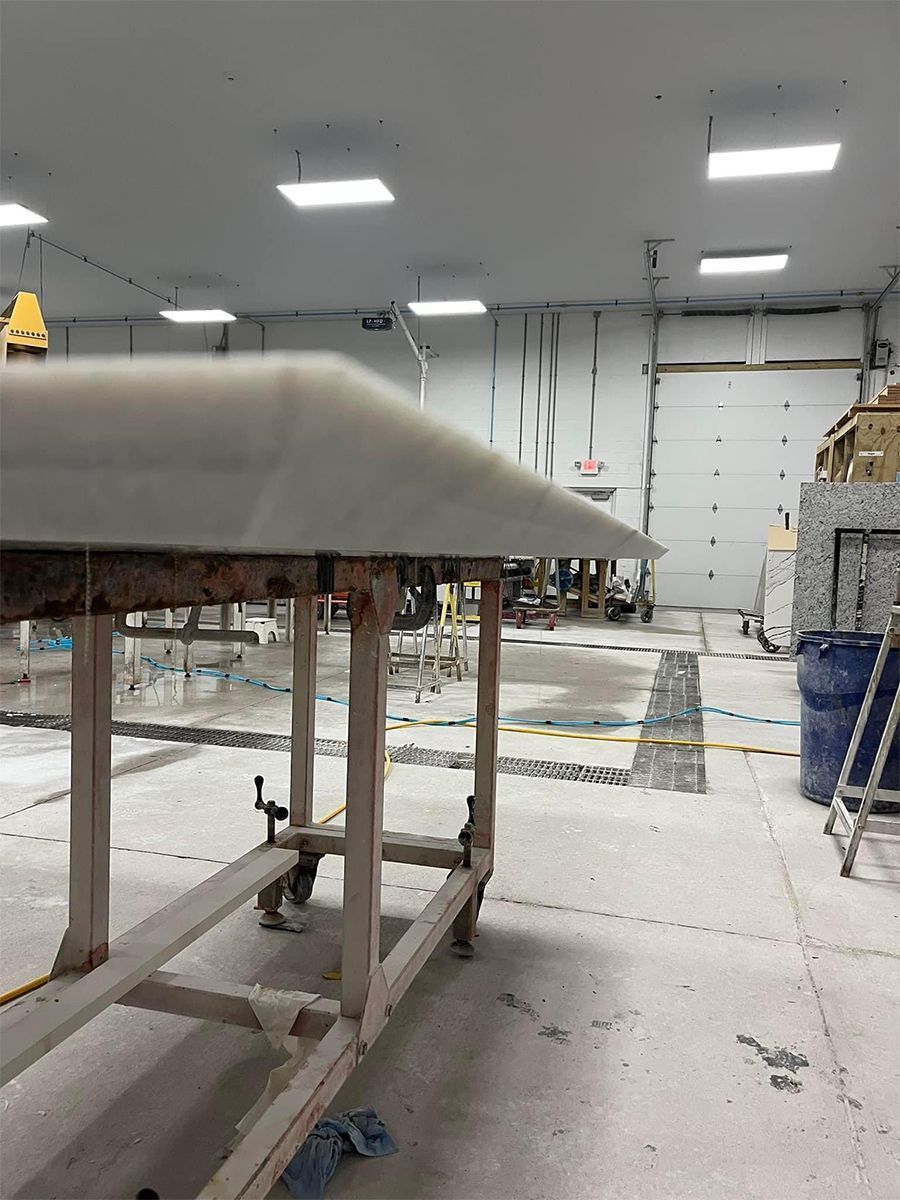 White countertop on a metal frame, in a workshop. A large door and other equipment are visible.