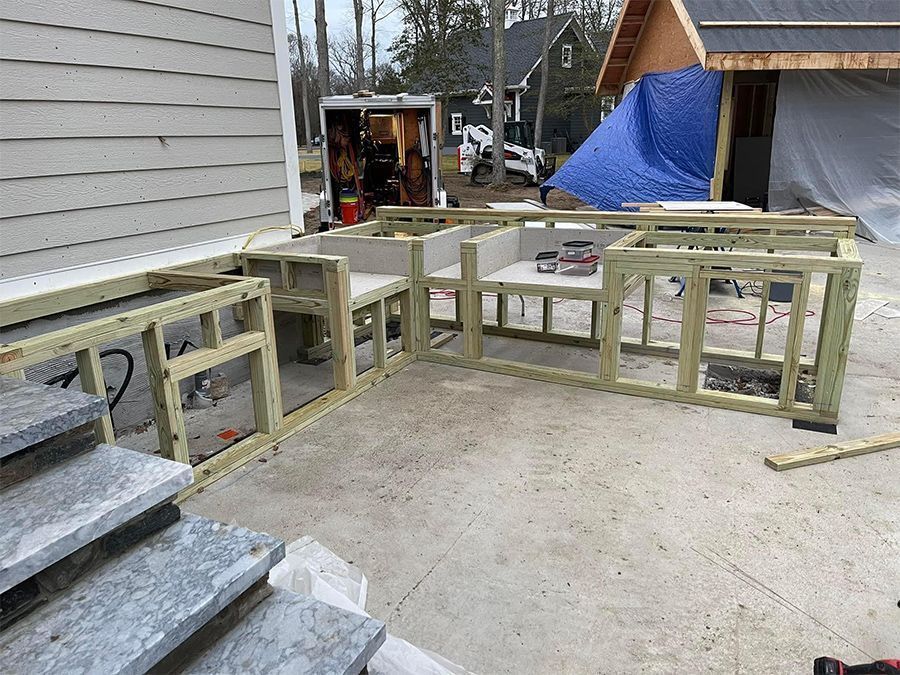 Outdoor kitchen frame under construction with concrete patio and granite steps.