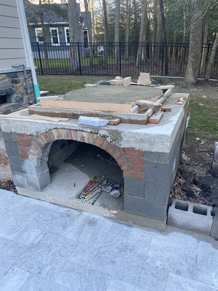 Outdoor brick pizza oven under construction on a patio.